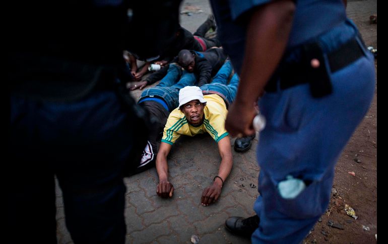 Un hombre se ve en el suelo tras su detención hoy en Katlehong, Johannesburgo.