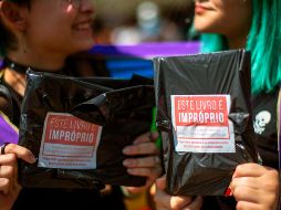 Mujeres muestran dos de los 14 mil libros de temas LGBT comprados y regalados en la bienal de Río de Janeiro por el youtuber Felipe Neto, en protesta contra la censura del alcalde.  AFP/Bienal do Livro do Rio