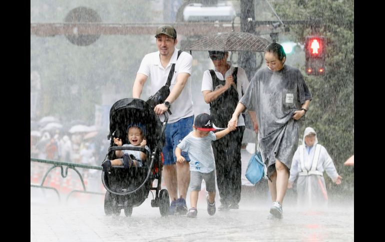 Una famlia camina bajo una intensa lluvia causada por el tifón. AP / Kyodo News