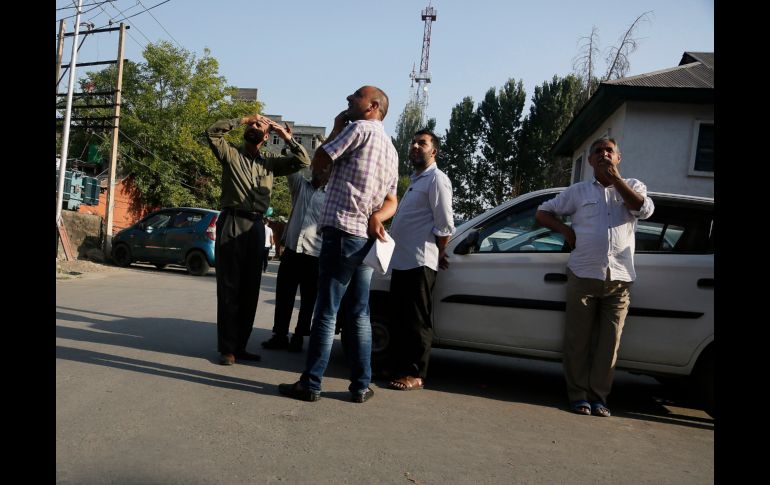 Kashmiri men look towards a buildings following tremors in Srinagar