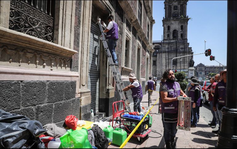 Trabajadores restauran y arreglan las fachadas de edificios y comercios dañados el jueves por encapuchados. NOTIMEX/Q. Blanco