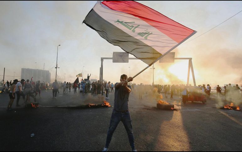 Uno de los inconformes agita la bandera iraquí en las protestas contra el desempleo. AFP