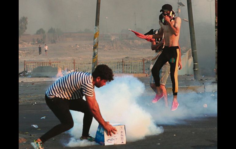 Rijosos intentan repeler los gases lacrimógenos de los oficiales en Bagdad. AP