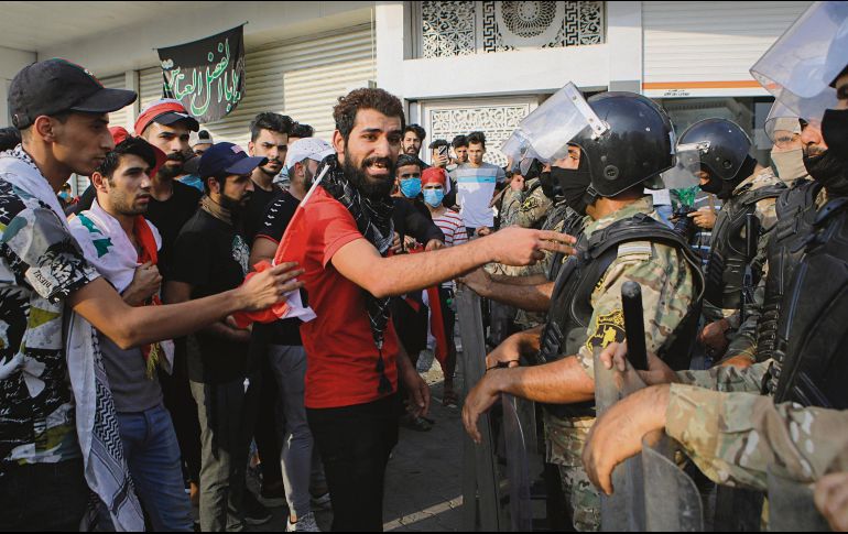Un grupo encara a los antimotines que resguardan un edificio público en Basora. AP