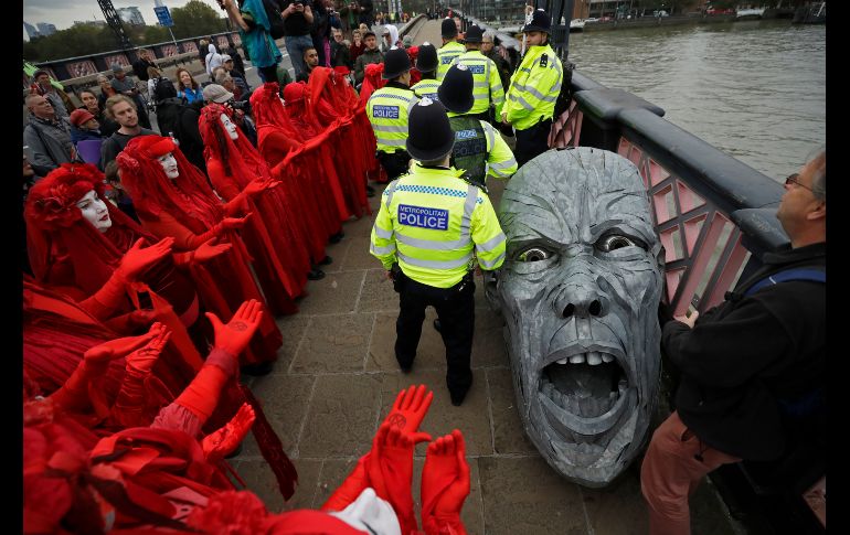 En Londres, manifestantes se reúnen alrededor de la cabeza de una estatua confiscada por la policía en el puente Lambeth. AP/M. Dunham
