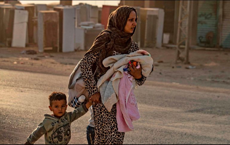Una mujer huye de una de las zonas afectadas por los bombardeos con sus hijos, en Siria. AFP/D. Souleiman