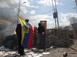 Manifestantes se ocultan tras una barricada cuando se cumplen 10 días de protestas contra el Gobierno este sábado, en Quito. EFE/J. Jácome