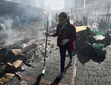 Una mujer barre los desechos abandonados en calles de Quito tras las protestas. AFP/L. Robayo