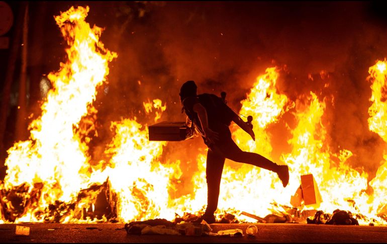Un manifestante alimenta el fuego encendido cerca de la Delegación del Gobierno en Barcelona. EFE/E. Fontcuberta