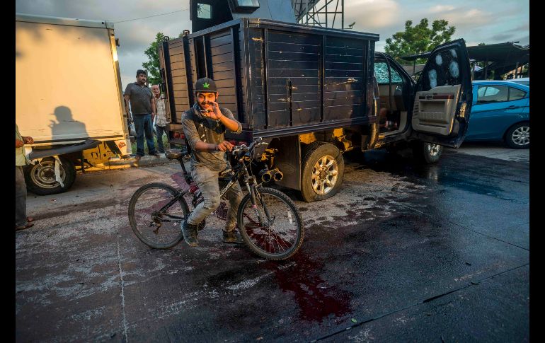 Un hombre recoge una bala en una calle con una mancha de sangre. AP/A. Zurita