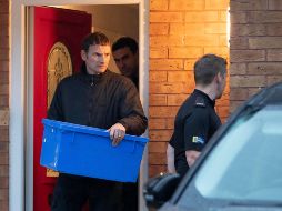 Policías salen de la casa de Joanna y Thomas Maher, dos de los detenidos, con una caja de evidencia. AP/J. Roberts