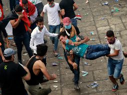 Manifestantes trasladan a un compañero herido durante una protesta en Bagdad. AP/H. Mizban