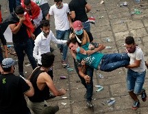 Manifestantes trasladan a un compañero herido durante una protesta en Bagdad. AP/H. Mizban