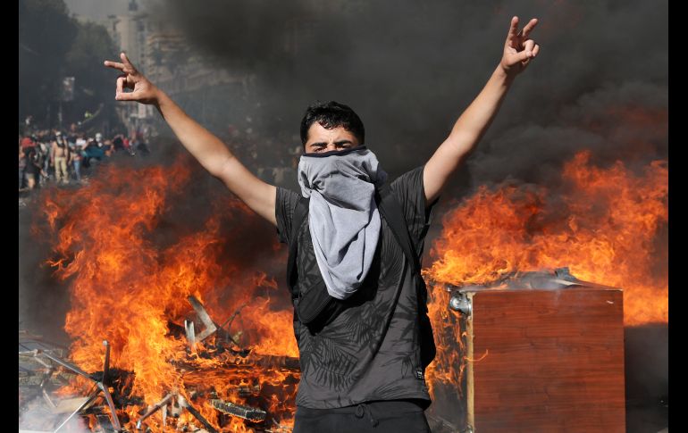 Un joven hace la señal de la victoria frente una barricada en llamas este lunes en Santiago. AP/R. Abd