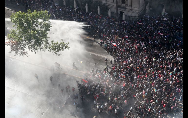 Policías arrojan chorros de agua contra manifestantes en Santiago. AP/E. Felix