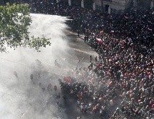 Policías arrojan chorros de agua contra manifestantes en Santiago. AP/E. Felix