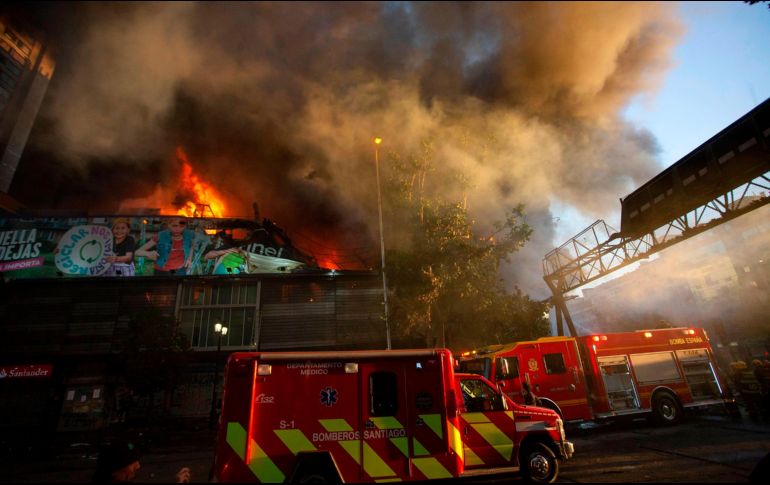 El fuego se propagó a dos altos edificios de oficinas colindantes, pero bomberos lograron evitar que las llamas se propagaran más allá. AFP/C. Reyes