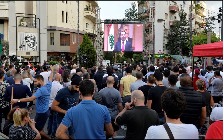 Miles de personas reaccionan mientras ven en la pantalla gigante la dimisión del primer ministro libanés, Saad Hariri. EFE/W. Hamzeh