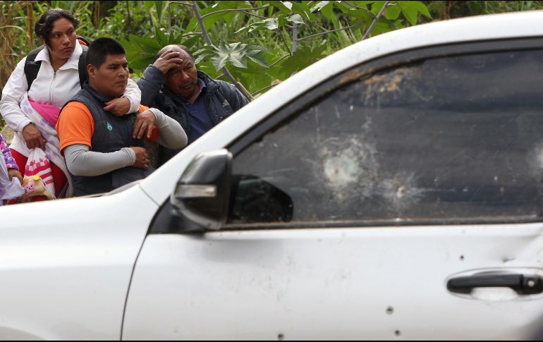 Varias personas observan el coche en el que viajaban los indígenas atacados; al auto se le aprecian varios impactos de bala. EFE/E. Guzmán