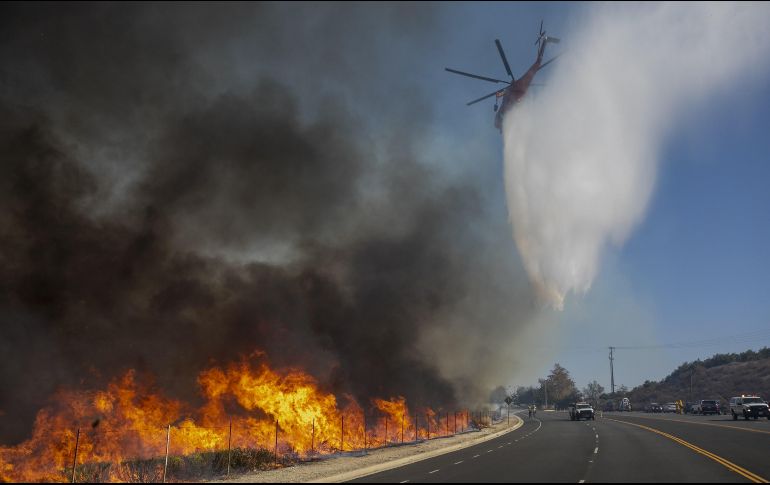 Un helicóptero descarga sobre una carretera en Simi Valley. AFP/D. McNew
