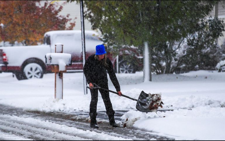 Una mujer despeja con una pala la nieve que se acumuló frente a su casa, en Illinois. EFE/T. Maury