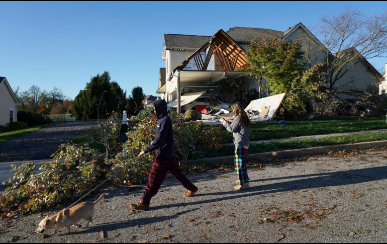 Dos personas que pasean a su perro pasan por uno de los árboles que cayeron debido al mal clima en Ohio. AP/J. Griffin-The Philadelphia Inquirer