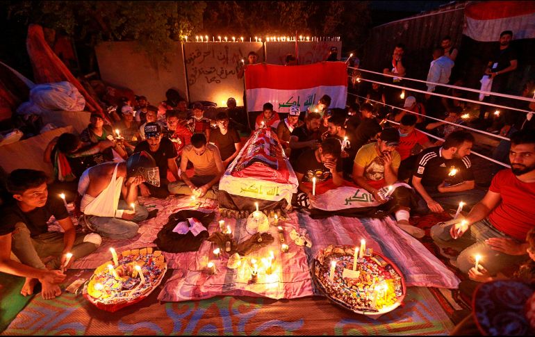 Habitantes oran junto a un ataúd simbólico por las víctimas mortales de las protestas en Bagdad. AP/H. Mizban
