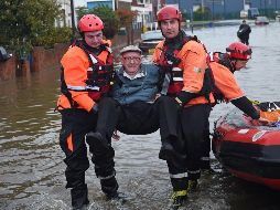 Cuerpos de rescate trasladan a un anciano que quedó atrapado en medio de las inundaciones a un lugar seguro. AFP/O. Scarff