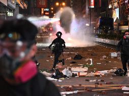 Manifestantes huyen luego de que la policía lanzara un cañón de agua en el distrito Mong Kok. AFP/P. Fong