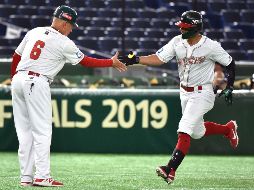 Jonathan Jones es recibido por el coach Martín Arzate al marcar la primera carrera del partido. AFP/K. Nogi