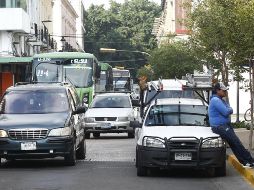 Un trabajador aguarda apoyado en su vehículo mientras el tráfico de la calle Juan Manuel se acumula. EL INFORMADOR/A. Camacho