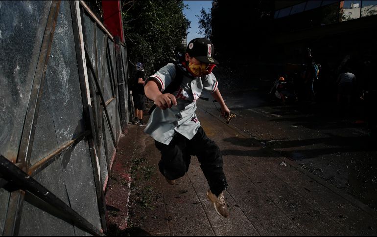 Manifestante chileno huye cuando se acerca un cañón de agua de la policía. AP/L. Hidalgo
