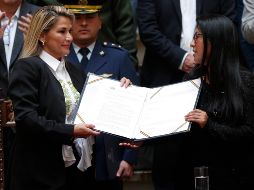 La presidenta interina Jeanine Áñez (i) sostiene el documento de la ley de urgencia junto a la presidenta del Senado, Mónica Eva Copa, en La Paz. AP/J. Karita