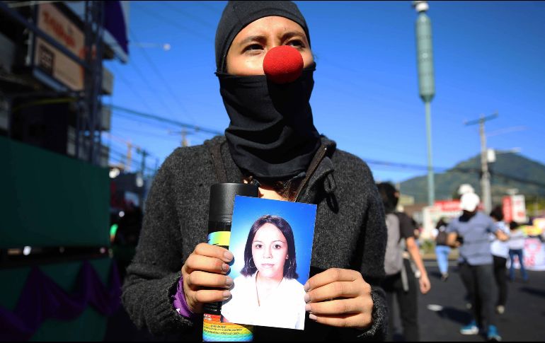 Una activista sostiene una fotografía de una joven asesinada, durante una marcha en San Salvador. EFE/M. Lemus