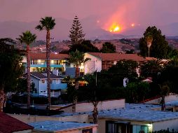 Las llamas alcanzan a verse de lejos tras una colina, en Santa Bárbara. AFP/K. Grillot