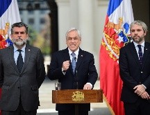 Piñera (c) urgió al Congreso para que despache proyectos de ley que establecen penas para los encapuchados, saqueadores y quienes levanten barricadas. AFP/J. Ordóñez