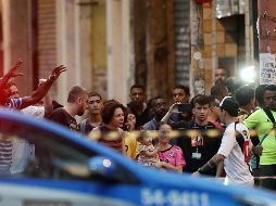 Curiosos observan a los policías que participan en un operativo este viernes, frente al bar donde un hombre mantiene a los rehenes. EFE/M. Sayão