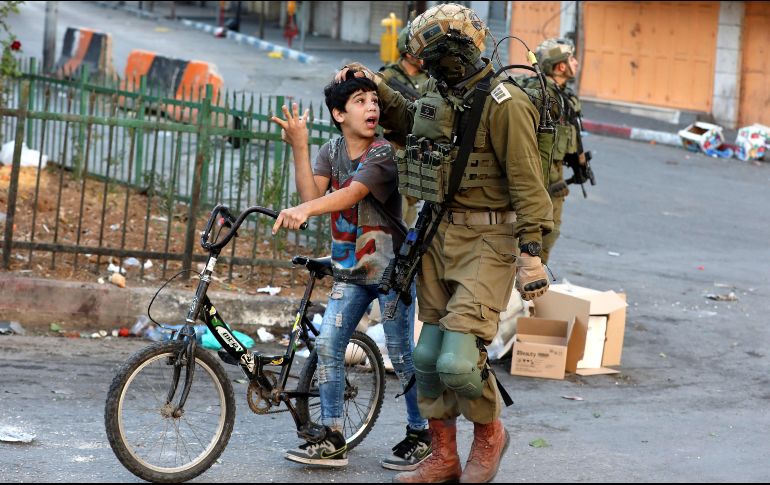 Un soldado israelí detiene a un niño palestino por arrojar piedras durante un enfrentamiento entre civiles palestinos y miembros del ejército israelí en la ciudad cisjordana de Hebrón. EFE/A. Al Hashlamoun