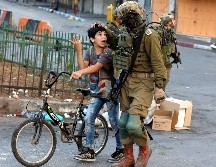 Un soldado israelí detiene a un niño palestino por arrojar piedras durante un enfrentamiento entre civiles palestinos y miembros del ejército israelí en la ciudad cisjordana de Hebrón. EFE/A. Al Hashlamoun