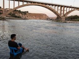La calma antes de la tormenta. Un hombre descansa en la orilla del Tigris, mientras las aguas, suben lentamente hasta sumergir a su pueblo, perdiéndose así uno de los lugares habitados más antiguos del mundo. GETTY IMAGES