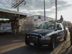 Policías estatales vigilan en el exterior de un local de lavado de automóviles, donde un grupo armado asesinó a dos personas. EFE/I. Villanueva