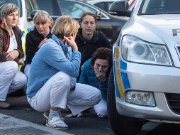 Varias enfermeras se esconden detrás de un coche de policía mientras los agentes persiguen al autor del tiroteo en el hospital de Ostrava. EFE/L. Kabon
