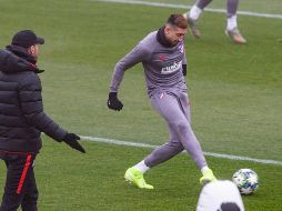 Héctor Herrera toca el balón bajo la mirada del técnico Diego Simeone, durante la práctica de ayer previo al juego. EFE/R. Jiménez