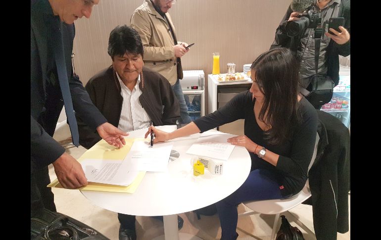 Evo Morales (2i) firma el documento en el que solicita formalmente refugio en Argentina, tras su llegada al aeropuerto internacional de Ezeiza este jueves, en la provincia de Buenos Aires. EFE/ESPECIAL/Carlos Girotti