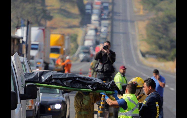 Elementos de Protección Civil trasladan los cuerpos de la zona del accidente en la  autopista. EFE/J. Mendoza