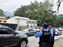 Dos miembros de la policía nacional resguardan las instalaciones de la morgue judicial del Ministerio Público hondureño. EFE/J. Valle