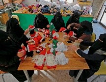 Una veintena de mujeres gazatíes, varias de las cuales llevan a sus hijos a la fábrica, preparan muñecos de Papá Noel y figuras de madera del árbol de Navidad. AFP/M. Abed