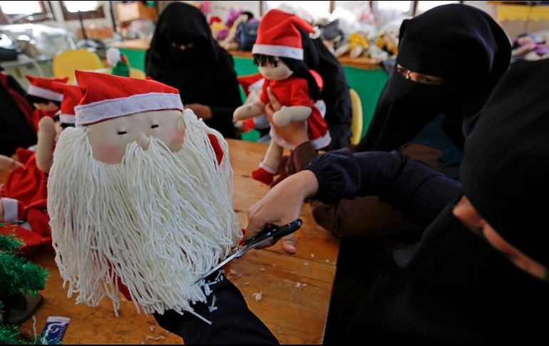 Una veintena de mujeres gazatíes, varias de las cuales llevan a sus hijos a la fábrica, preparan muñecos de Papá Noel y figuras de madera del árbol de Navidad. AFP/M. Abed