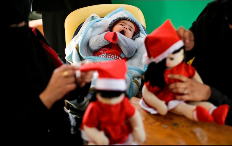 Una veintena de mujeres gazatíes, varias de las cuales llevan a sus hijos a la fábrica, preparan muñecos de Papá Noel y figuras de madera del árbol de Navidad. AFP/M. Abed
