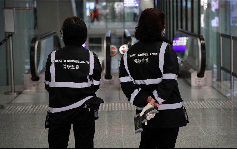 Oficiales de salubridad con escáneres de temperatura en el aeropuerto de Hong Kong. AP/A. Wong